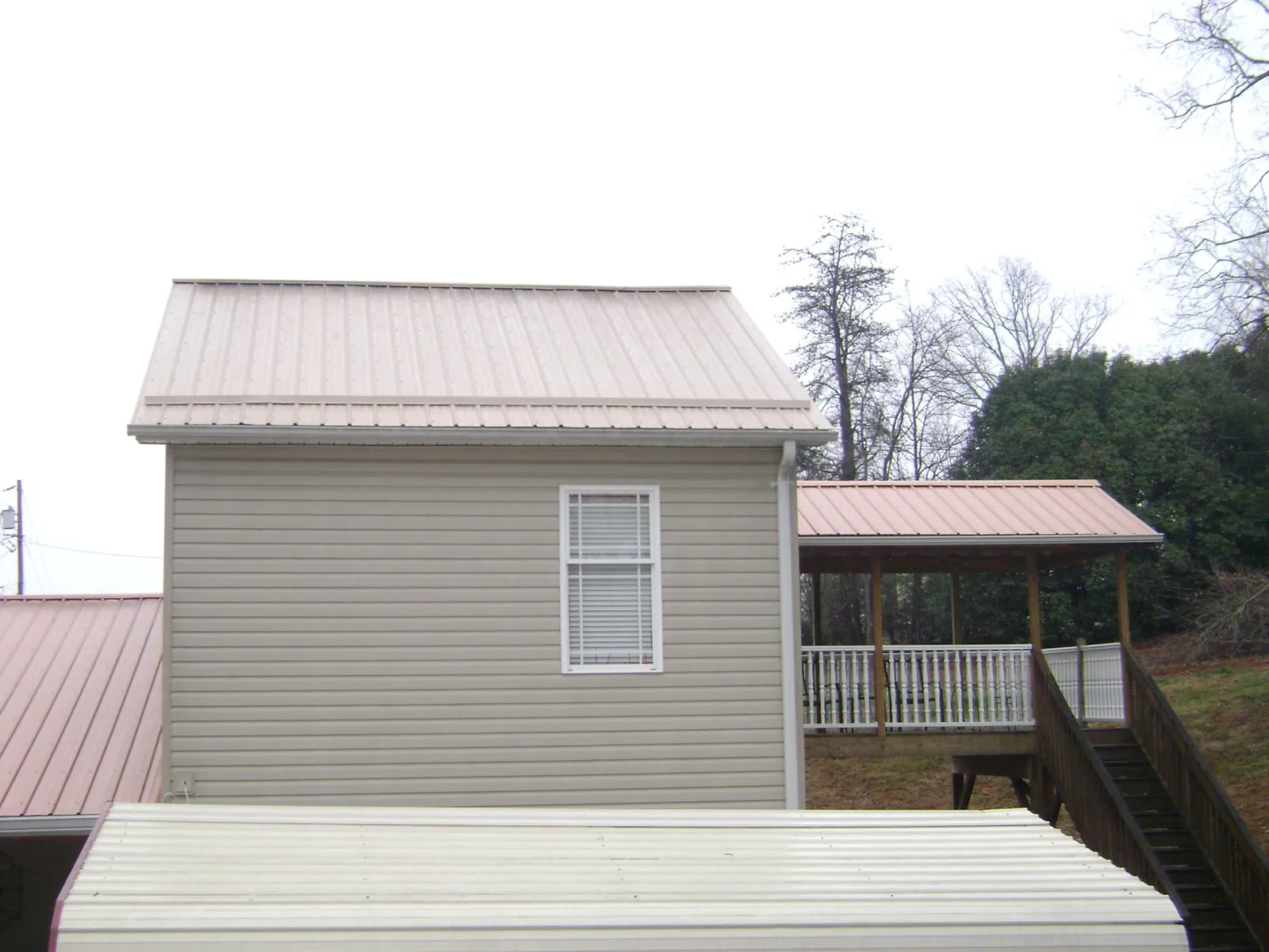 Tan metal roofs on a two story addition and attached porch, from a Roof Replacement job in Ferndale